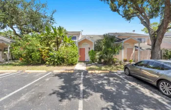 Property exterior featuring a coral-hued entry door, arched entryway, and mature landscaping