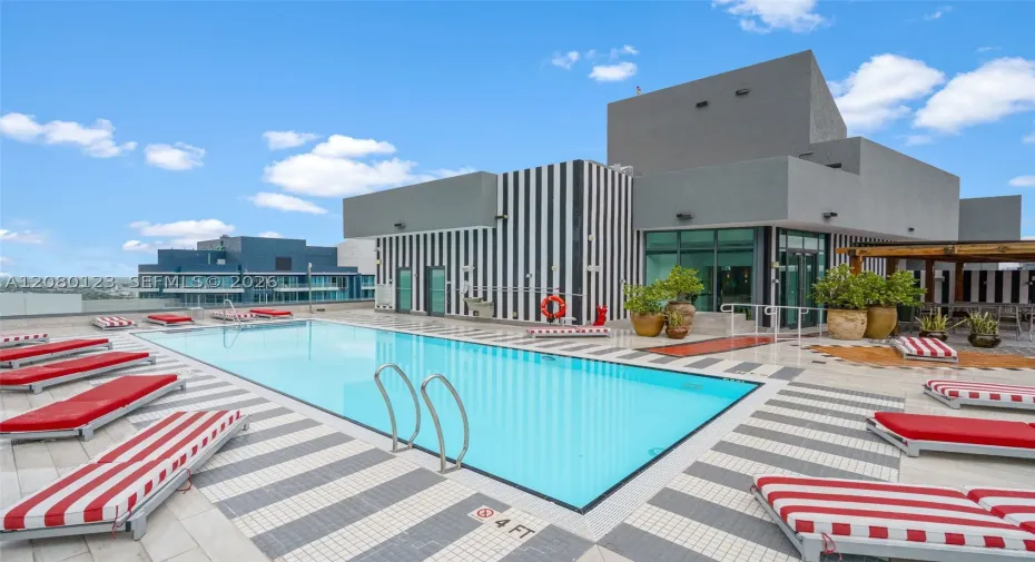 Rooftop pool with signature red-striped chaise lounges - elevated relaxation at SLS Brickell Dua.