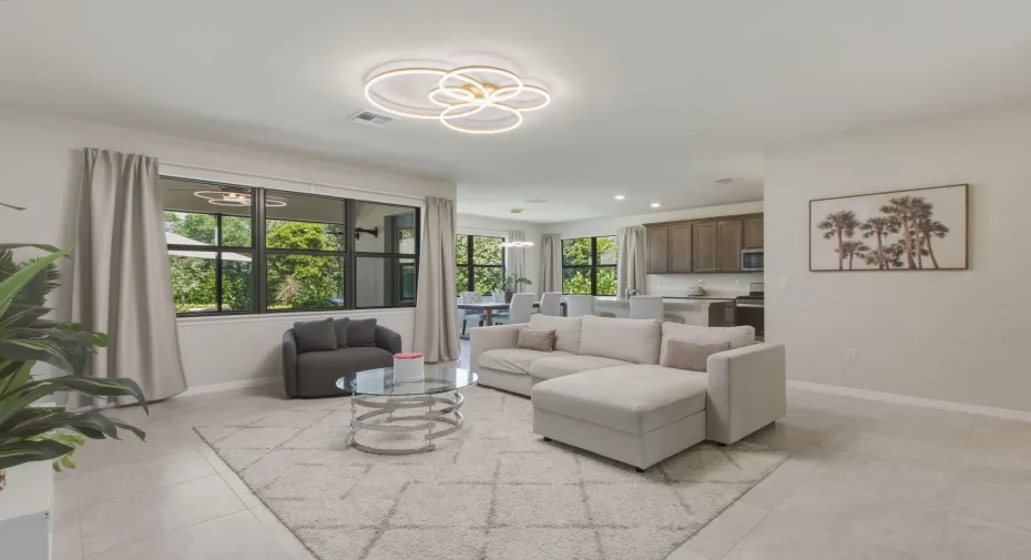 Open-concept living area with large windows, light tile flooring, and recessed lighting