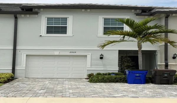 Two-story exterior with a light blue stucco finish, white trim, and a shingled roof