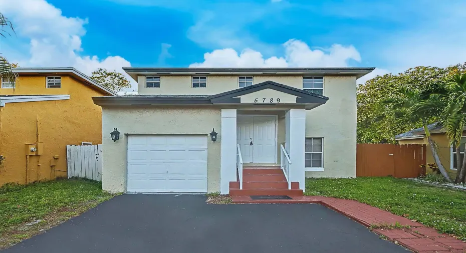 Two-story stucco exterior featuring a covered entry, white double doors, and a single-car garage
