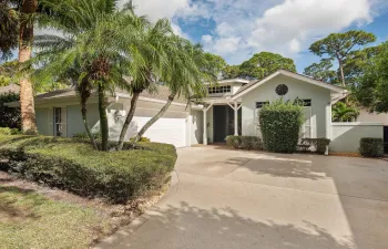 Contemporary single-story residence featuring a clean stucco exterior, arched entryway with circular window detail, and a wide concrete driveway