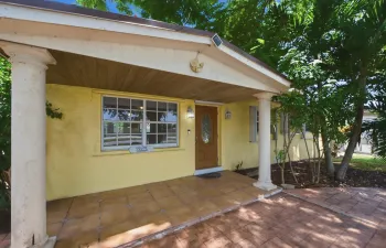 Covered entry with support columns, tiled flooring, wood-finish ceiling, and a paneled front door with oval glass insert