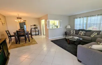 Tiled flooring throughout, dining area with chandelier, pass-through window, and multiple windows