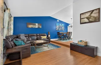 Vaulted ceiling, wood-finish flooring, accent wall, step-up dining area, and pendant lighting