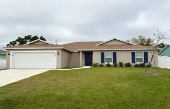 Single-story residence featuring a brown shingle roof, beige exterior stucco, and a dark blue front door