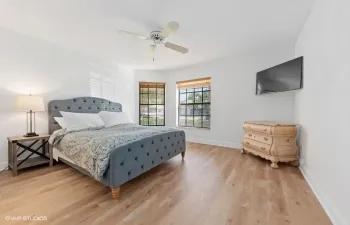 Wood-finish flooring, ceiling fan, multiple windows with blinds, wall-mounted television