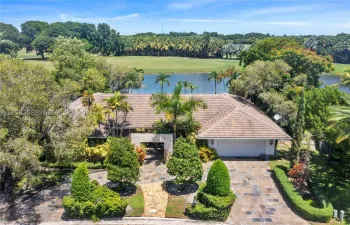Beautifully landscaped home with a paver driveway, two-car garage, and scenic lake and golf course views.
