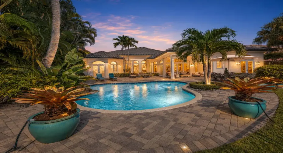 Curved swimming pool with an integrated spa, surrounded by a paver patio