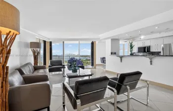 An open, sun-filled living space with floor-to-ceiling views that capture both the tranquil waterfront and the vibrant skyline