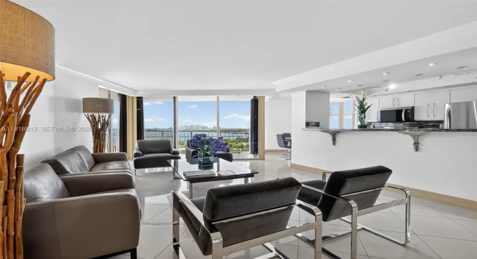 An open, sun-filled living space with floor-to-ceiling views that capture both the tranquil waterfront and the vibrant skyline
