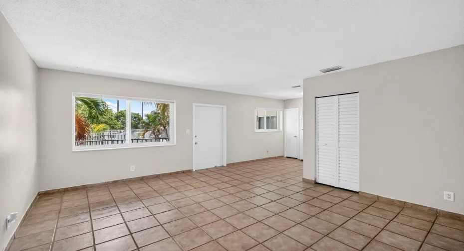 Neutral wall paint, tile flooring, louvered closet doors, and multiple windows