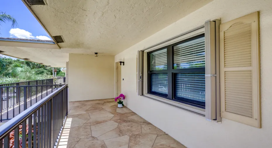 Exterior walkway featuring irregular cut tile flooring and wrought iron railings