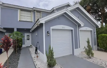 Stucco exterior with white trim, two white paneled garage doors, and a white front entry door with a frosted glass insert
