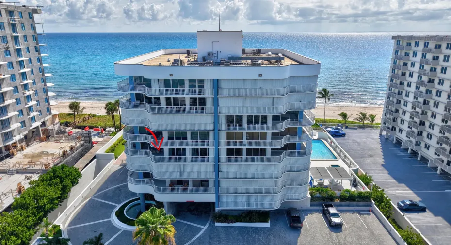 Coastal high-rise architecture with expansive balconies, a ground-level swimming pool, and direct beach access
