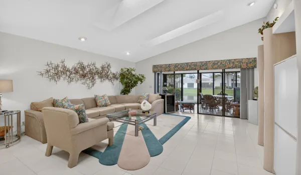 Vaulted ceiling with recessed lighting, tile flooring, and a full wall of glass sliders overlooking small lake
