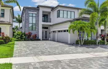 Contemporary two-story residence featuring a paver driveway, an integrated two-car garage, and a modern grey and stone facade