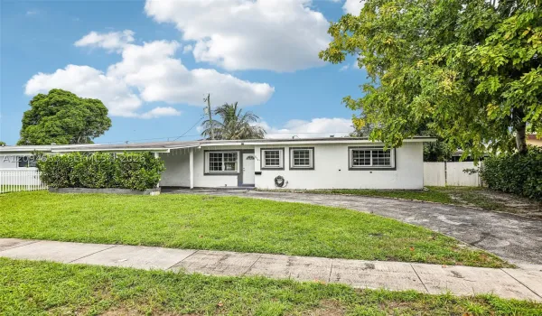 Front of the home with circular driveway and lawn