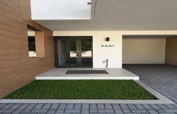 Modern entry with wood-panel siding, large format entry door, and integrated wall sconce