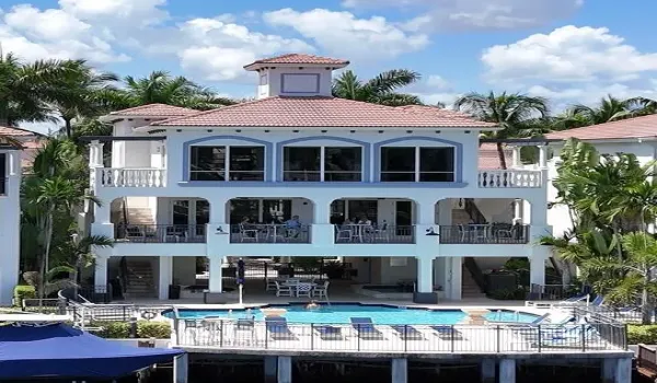 Mediterranean-style architecture with tile roofing, a central swimming pool with surrounding deck, multiple covered balconies, and a private dock with boat slips