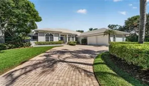 Paved driveway, manicured lawn, lush landscaping, arched windows, and a two-car side entry garage