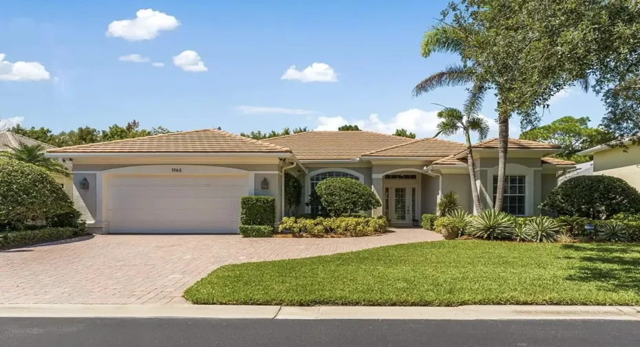 Exterior front of home with extended paver driveway and lush tropical landscaping