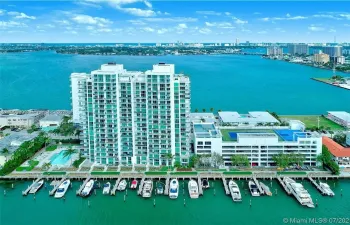 High-rise residential building featuring private boat slips, deep-water dockage, an outdoor swimming pool, and dedicated tennis courts