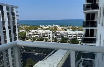 Ocean horizon, surrounding buildings, and glass balcony railing