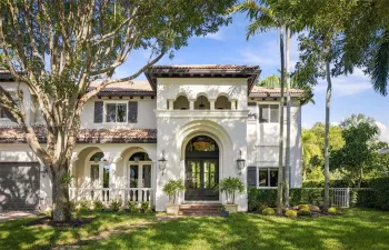 Mediterranean-style exterior featuring a clay tile roof, arched entryway, upper-level loggia, stucco facade, and symmetrical louvered shutters