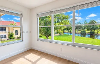 Stunning lake view from bright living space with natural light, impact windows, and wood-look floors.