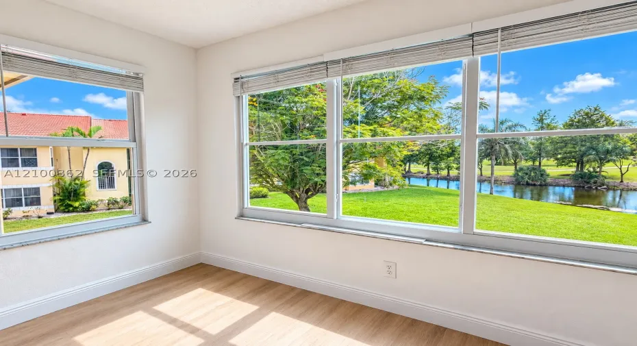 Stunning lake view from bright living space with natural light, impact windows, and wood-look floors.