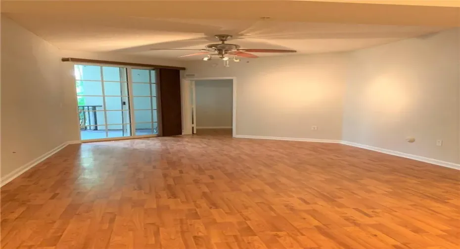 Wood-finish flooring, sliding glass doors, ceiling fan with integrated lighting, and a neutral color palette