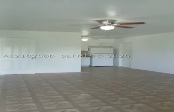 Recessed kitchen area with white cabinetry, white refrigerator, and ceiling-mounted light fixture