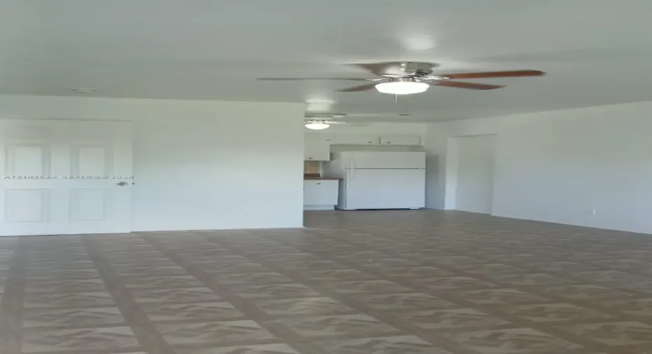 Recessed kitchen area with white cabinetry, white refrigerator, and ceiling-mounted light fixture