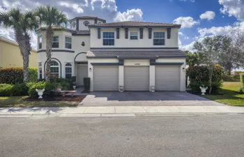 Stucco exterior with a tiled roof, three-car garage, bay window, and arched entryways