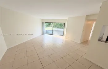 Open-concept area featuring light-toned tile flooring, neutral wall paint, and sliding glass doors with access to an exterior​​‌​​​​‌​​‌‌​‌‌​​​‌‌​‌​‌​‌​​​‌​​ patio