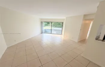 Open-concept area featuring light-toned tile flooring, neutral wall paint, and sliding glass doors with access to an exterior patio