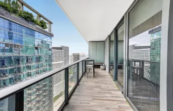 Private balcony featuring wood-finish tile flooring, a glass panel railing, and expansive floor-to-ceiling glass sliding doors