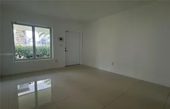 Neutral interior space featuring polished tile flooring, white wall finishes, a single-panel entry door, and a single-pane window