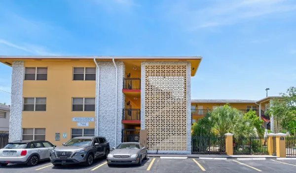 Multi-story building with a yellow exterior finish, textured white architectural elements, and black metal balcony railings