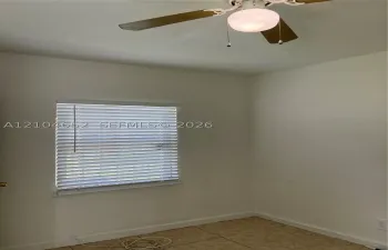 Room featuring neutral wall paint, tile flooring, window with horizontal blinds, and a ceiling fan with integrated lighting
