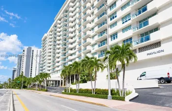 High-rise exterior featuring private balconies, floor-to-ceiling glass panels, manicured landscaping, and a multi-level concrete facade