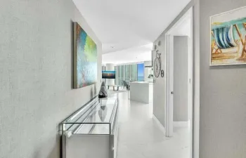 Hallway featuring textured wall coverings, recessed lighting, and white tile flooring