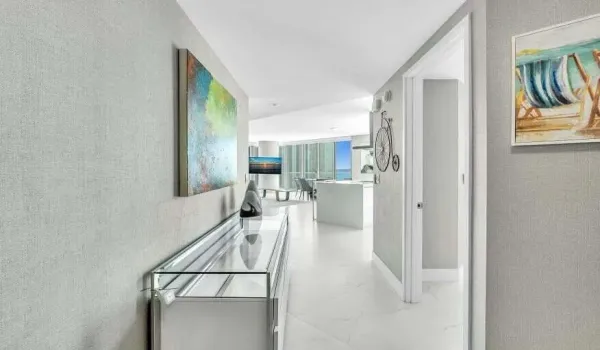 Hallway featuring textured wall coverings, recessed lighting, and white tile flooring