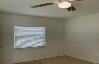 Room featuring neutral wall paint, tile flooring, window with horizontal blinds, and a ceiling fan with integrated lighting