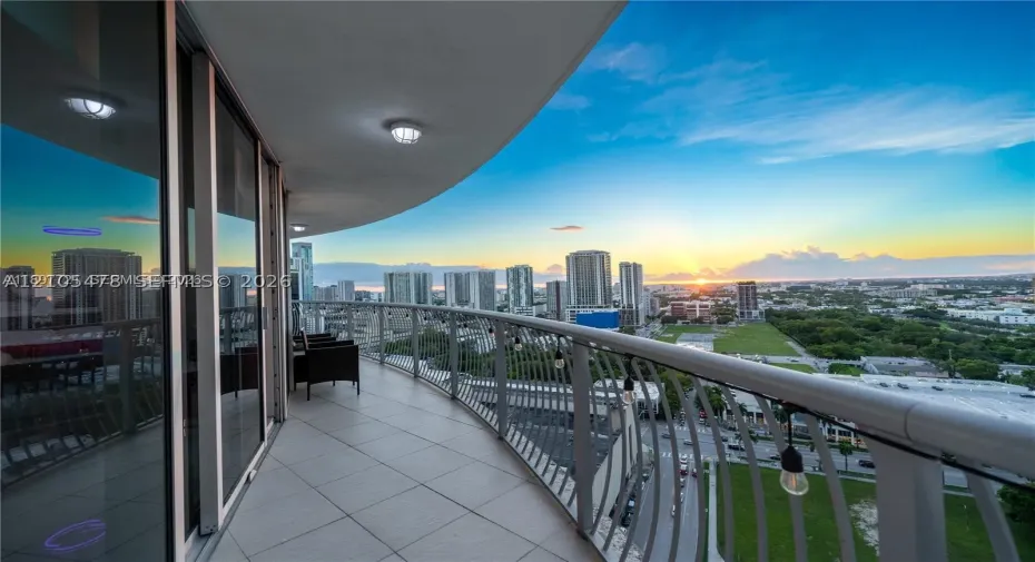 Expansive curved balcony featuring tiled flooring and a metal railing