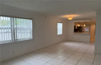 White tile flooring, crown molding, white walls, built-in breakfast bar with pendant lighting, and a prominent window
