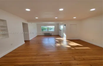Hardwood flooring, recessed ceiling lighting, built-in shelving, and a bright window with exterior scenery