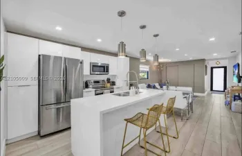 Modern kitchen featuring white cabinetry, stainless steel appliances, a center island with sink, and pendant lighting