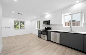 Kitchen featuring two-tone cabinetry, stainless steel appliances, light-toned wood-finish flooring, recessed lighting, and solid-surface countertops